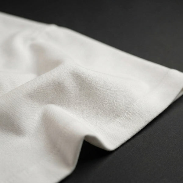 Close-up of high-quality white cotton fabric showing its thick, luxurious texture and structured drape.